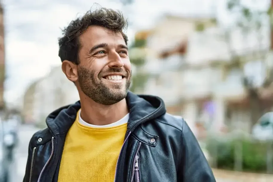 Homem sorridente de casaco de cabedal, ao ar livre